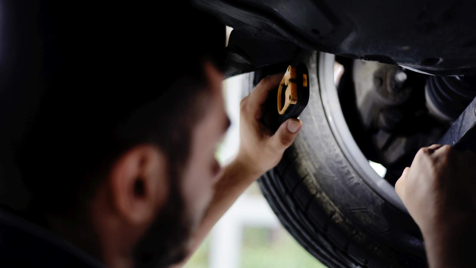 Mechaniker prüft ein Rad an einem angehobenen Fahrzeug